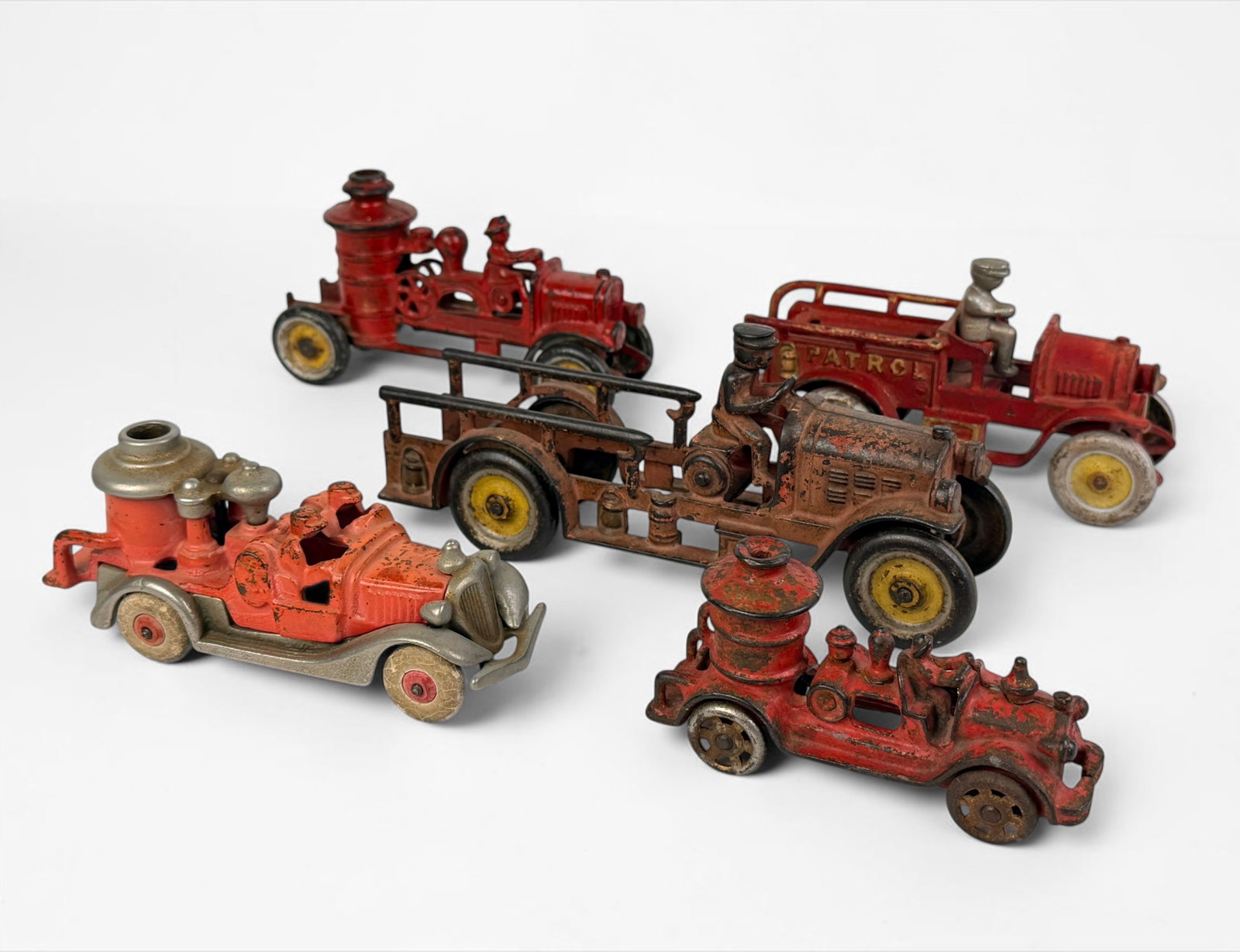 (5) Antique Cast Iron Firetrucks (I): Includes brands Hubley, Kenton, and more. Dimensions of Largest: 4" x 8 1/2" x 2 1/4" Condition: Rust and loss of pigment throughout. Wear to the rubber wheels