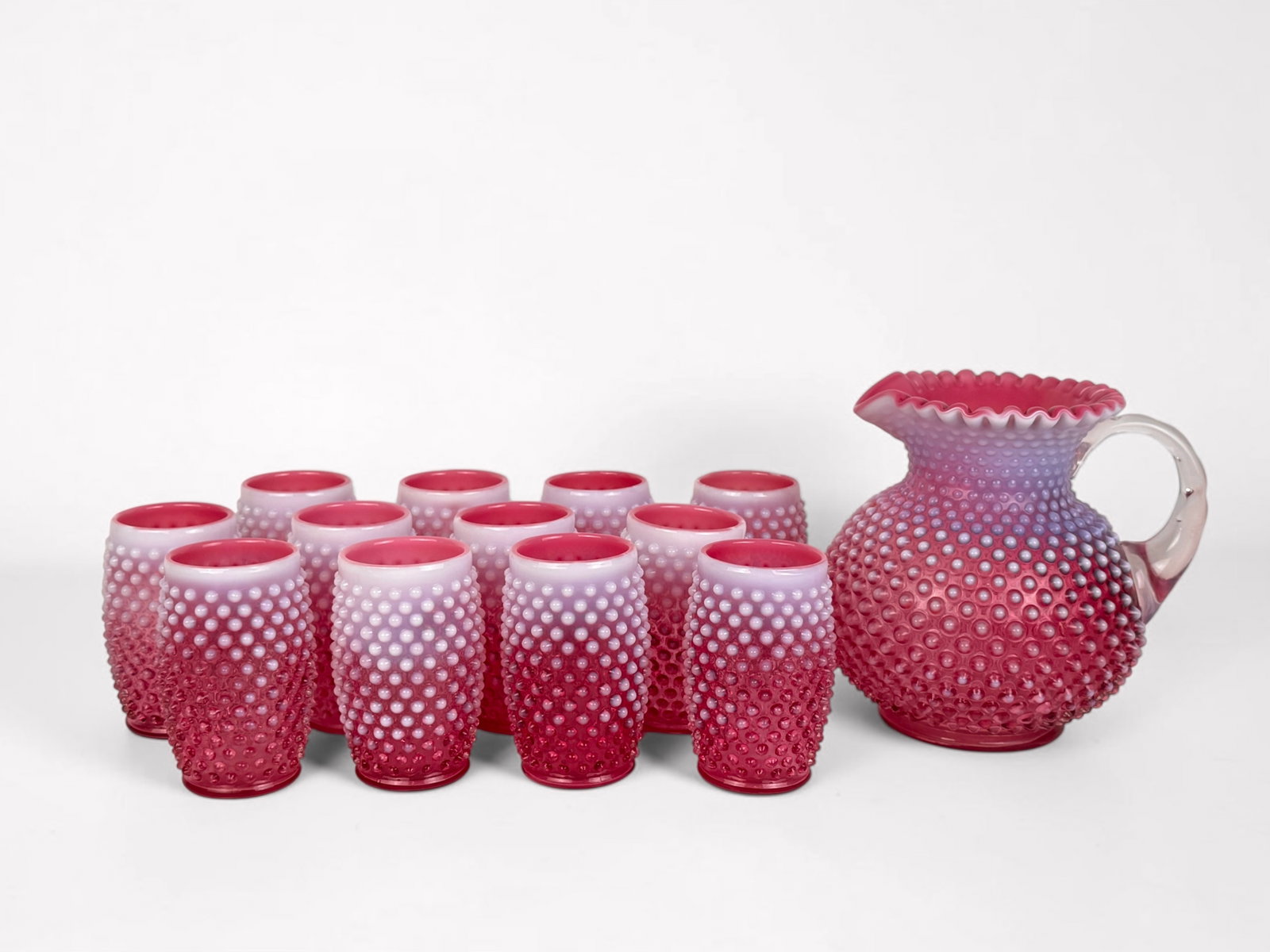 Pink Fenton Glass Pitcher Hobnail Set: Set includes (1) Pitcher and (12) Glasses Pitcher: 7 3/4" Tall x 8 1/2" Widest Point Cup: 5" Tall x 2 1/2" Wide Condition: The set is in very good