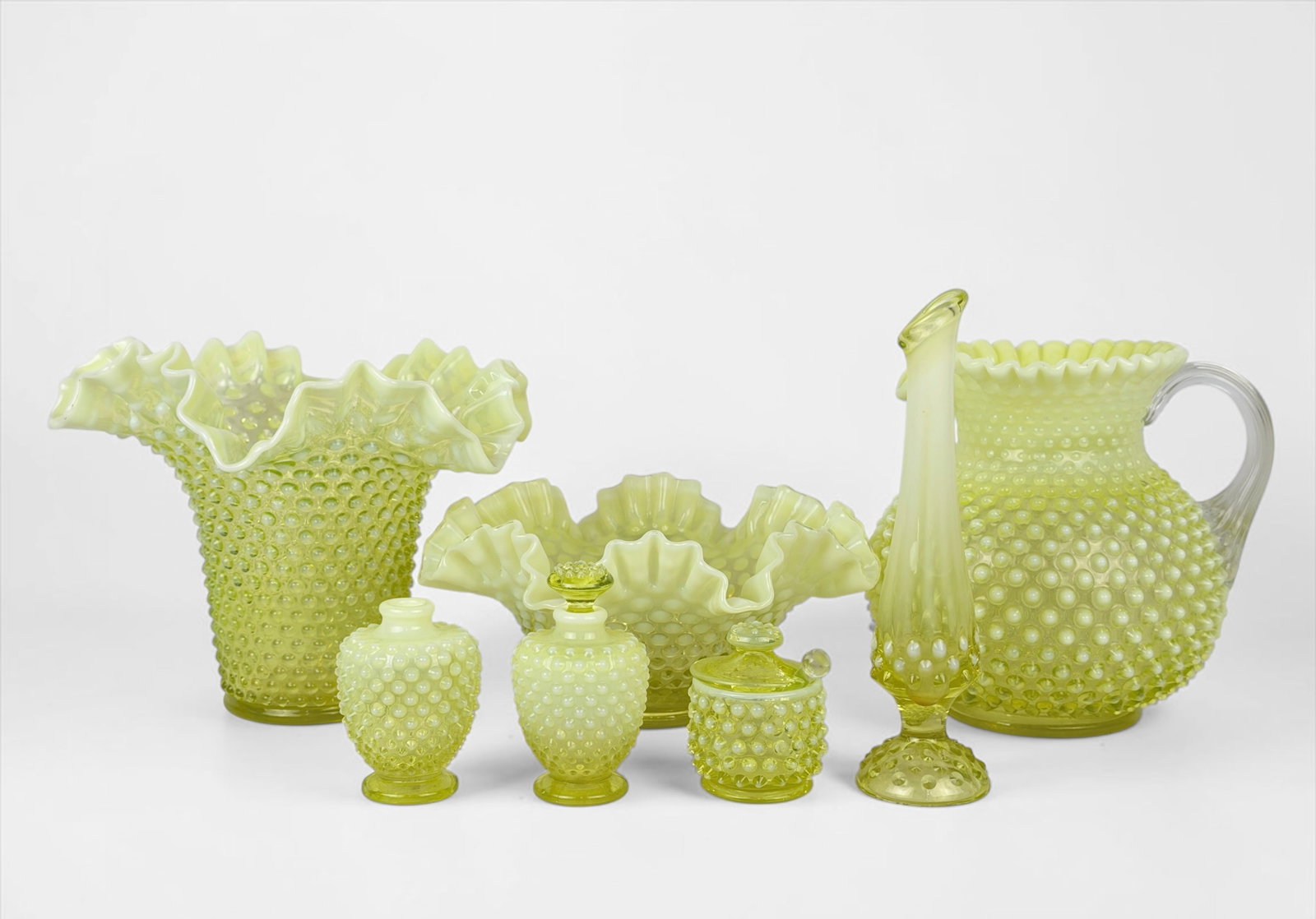 (7pcs) Uranium Glass Fenton Glassware: Largest Piece: 8" Tall x 9" Diameter Smallest Piece: 3 1/2" Tall x 2 1/2" Diameter Condition: The glassware is in good condition. Please see images for details.