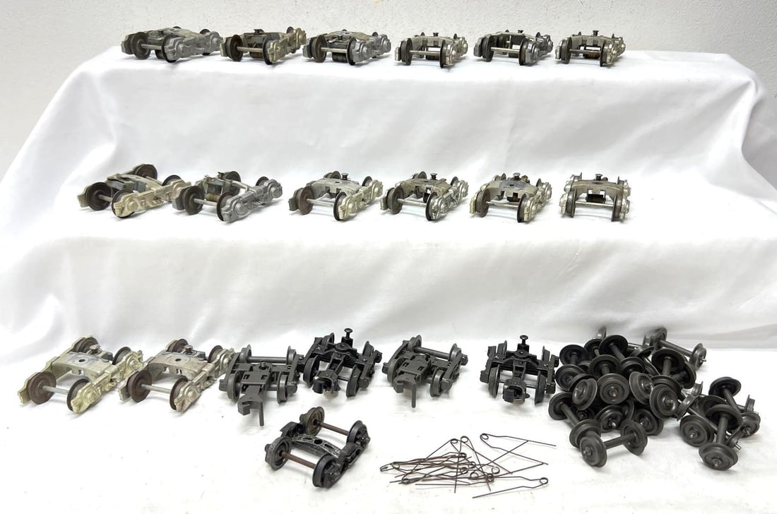 Fourteen O Gauge 4 wheel truck assemblies with pick-up rollers: Fourteen die-cast O Gauge 4 wheel truck assemblies with pick-up rollers (run), two plastic truck assemblies with wheels and couplers (unrun), twenty plastic wheels on metal axles (unrun), four axle se