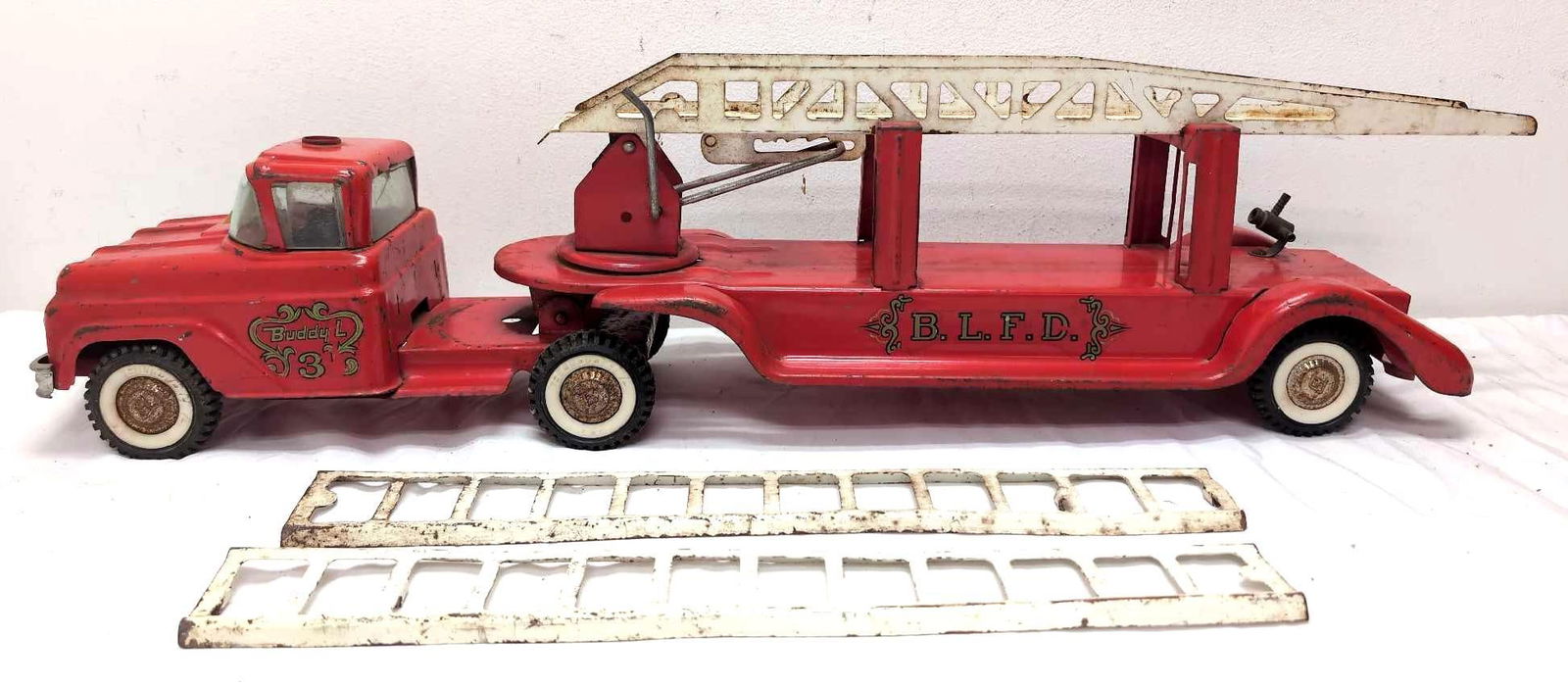 Vintage 1950s Buddy L Hook and Ladder Pressed Steel Fire Truck: Buddy L pressed steel fire truck. Truck as all it wheels and they roll. Miner paint chips and dents. Great find. Truck is approximately 27" long and 8" tall. Missing red light on top. Please view the