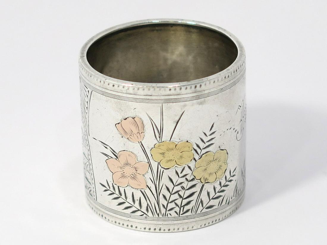 1 7/8 in - Coin Silver Mixed Metal Antique American Floral Napkin Ring: Dimensions (d x h): 1 7/8 x 1.75 in There is a ding pointed at with a red arrow.