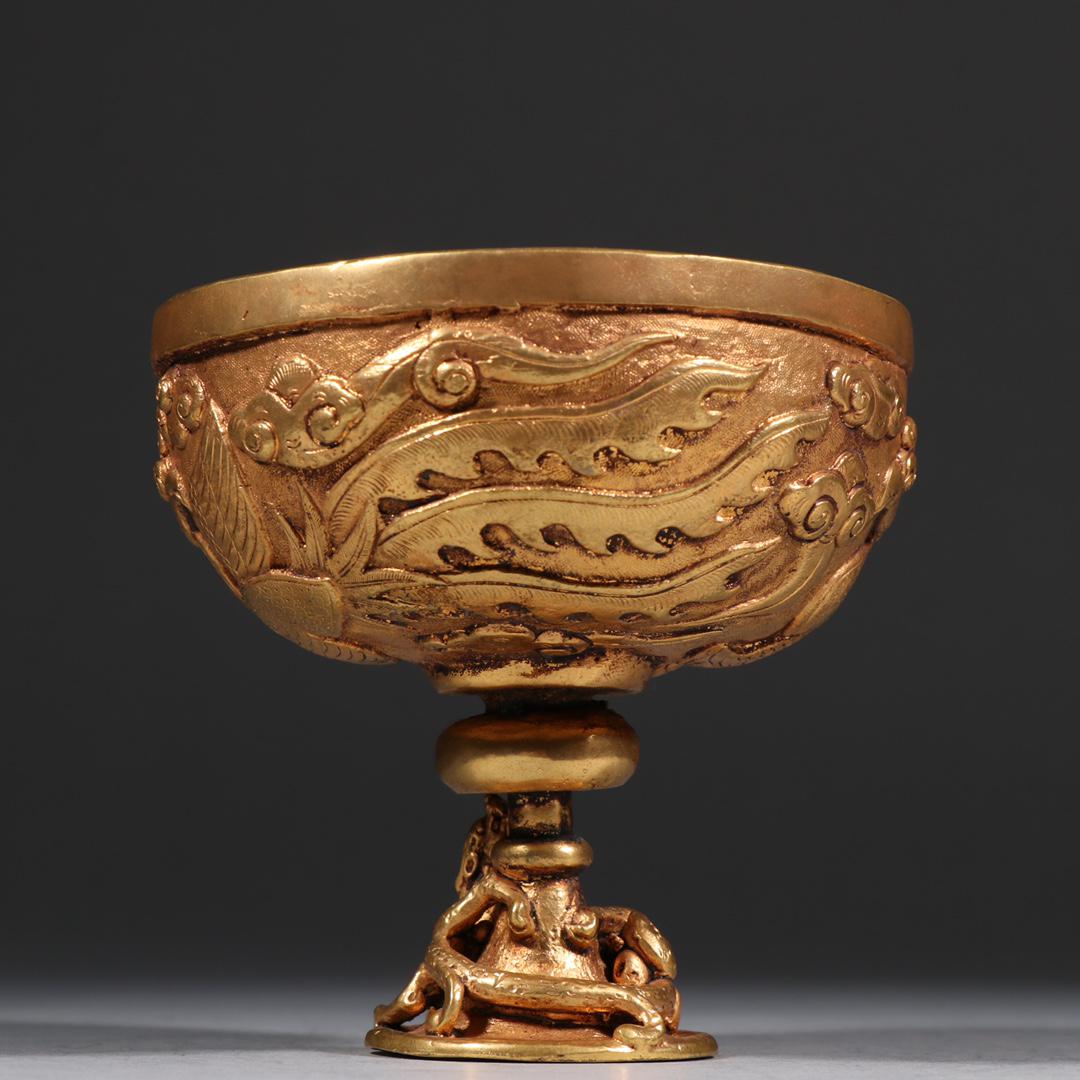 A Gilt-Bronze Wine Stemcup: A Gilt-Bronze Wine Stemcup. Finely cast on its body with phoenix and ruyi-head cloud patterns. Chinese Qing Dynasty. Size:10cmx9.3cm. Weight:622g.