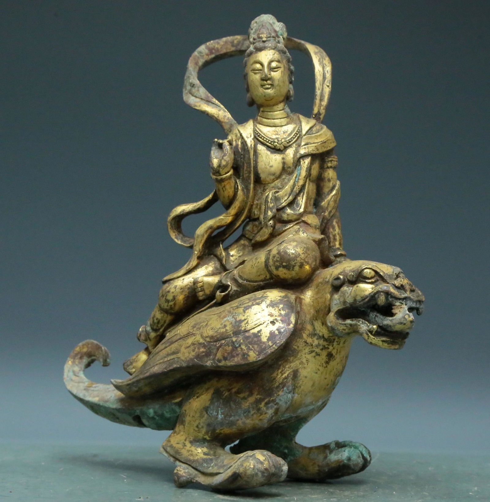 A Superb Gilt-Bronze Figure Of Bodhisattva: A Superb Gilt-Bronze Figure Of Bodhisattva. The figure is seated on a mythical beast, body rendered clad in a long, flowing robe, the voluminous drapery elegantly cascading in folds, also wearing a ce