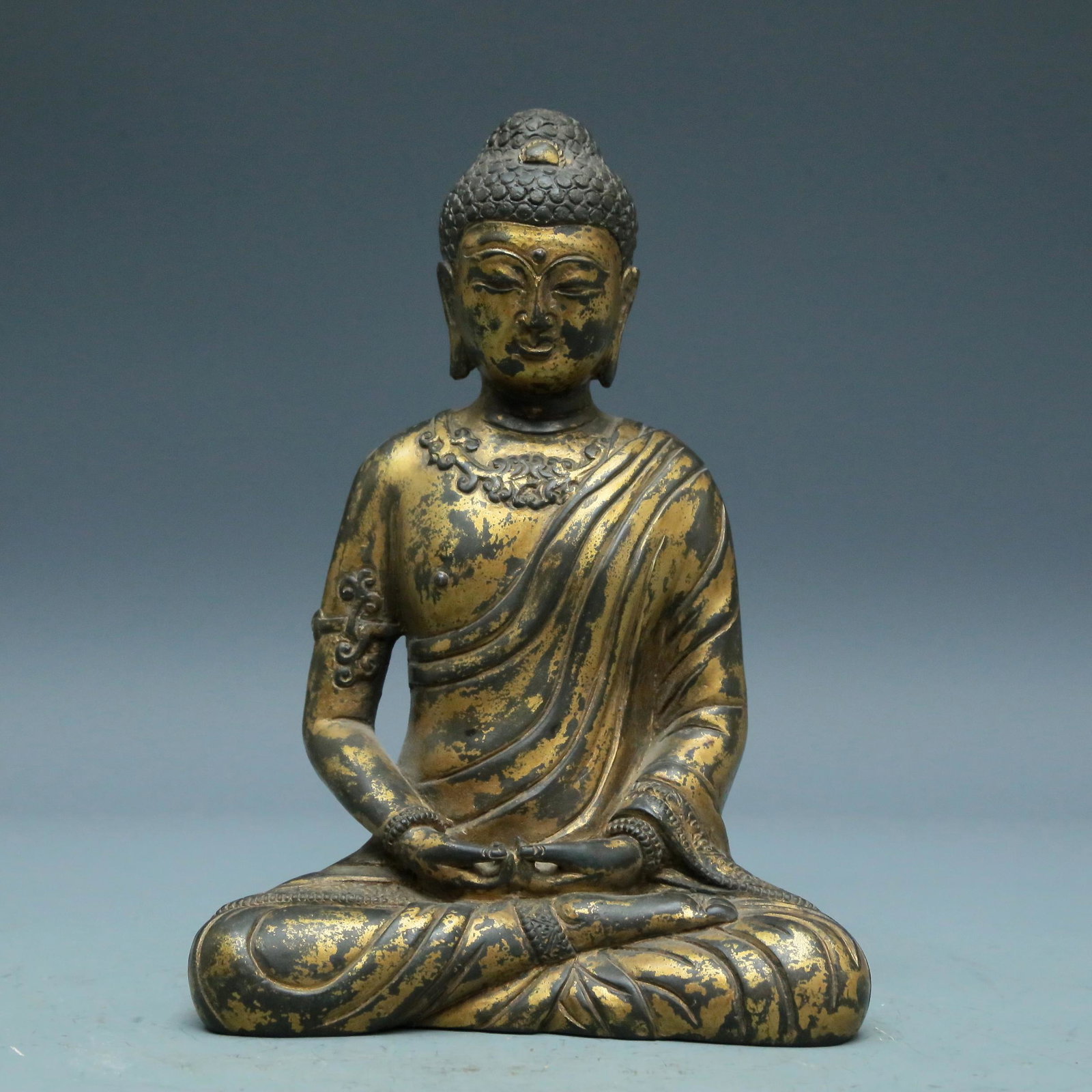 A Superb Gilt-Bronze Figure Of Buddha Shakyamuni: A Superb Gilt-Bronze Figure Of Buddha Shakyamuni. Superbly and sensitively sculpted in the form of a seated Buddha Shakyamuni, with well-defined arched eyebrows juxtaposed with the prominent nose abov