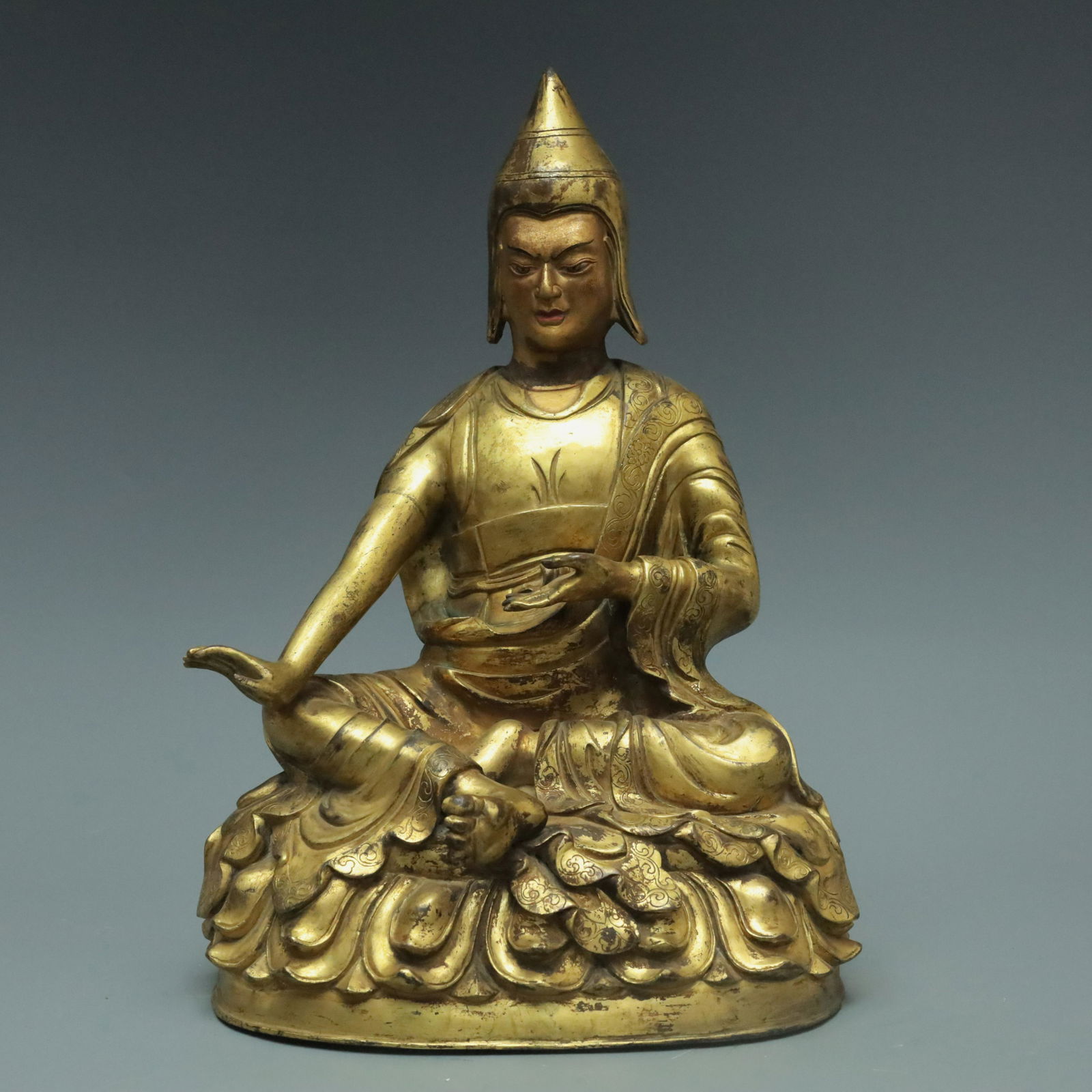 A Magnificent Gilt-Bronze Figure Of Mahasiddha: A Magnificent Gilt-Bronze Figure Of Mahasiddha. The figure with a dignified expression is seated, body rendered clad in long, flowing robes, the voluminous drapery elegantly cascading in folds, also w