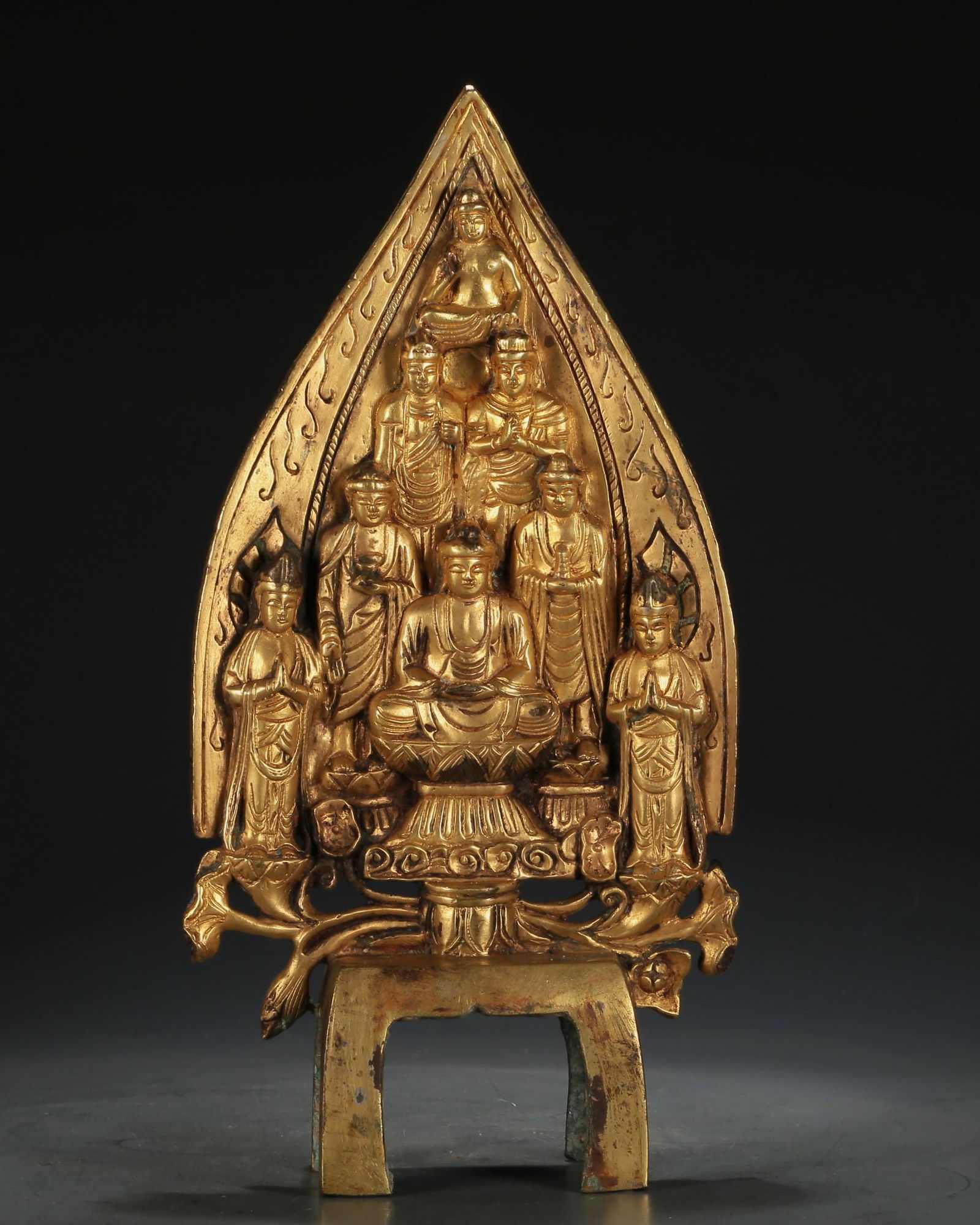 A Magnificent Gilt-Bronze Figure Of Buddha Shakyamuni: A Magnificent Gilt-Bronze Figure Of Buddha Shakyamuni. The figure is seated, body rendered clad in long, flowing robes, the voluminous drapery elegantly cascading in folds, accompanied by several atte