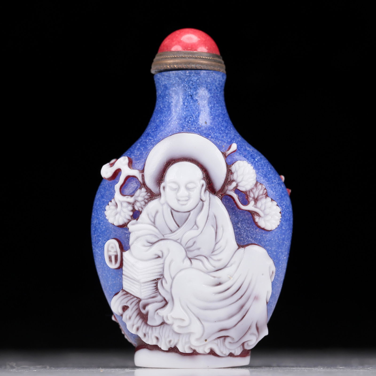 A Wonderful Polychrome Overlay Blue Snowflake Glass 'Arhat' Snuff Bottle: A Wonderful Polychrome Overlay Blue Snowflake Glass 'Arhat' Snuff Bottle. Carved with two jubilant bald figures, each's body rendered clad in long, flowing robes, the voluminous drapery elegantly casc