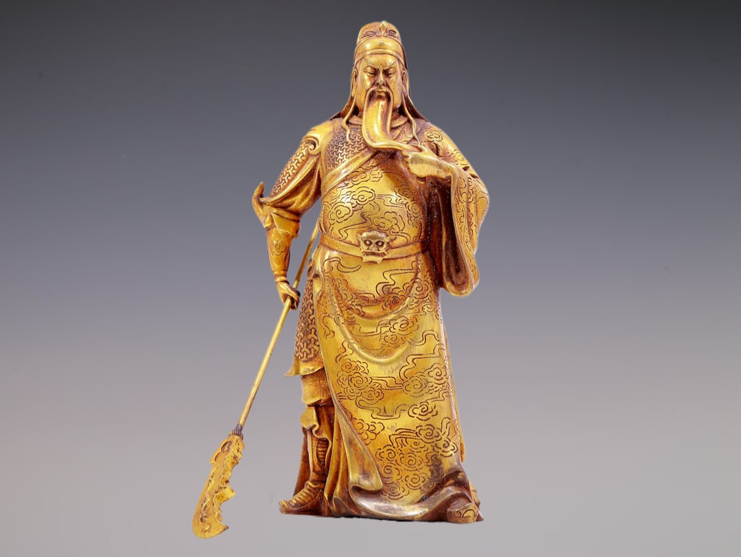 A Brilliant Gilt-Bronze Figure Of Guan Gong: A Brilliant Gilt-Bronze Figure Of Guan Gong. The bearded figure is stood with a serious expression, one hand holding a holy weapon, body rendered clad in an armor and a long, flowing robe with 'auspic