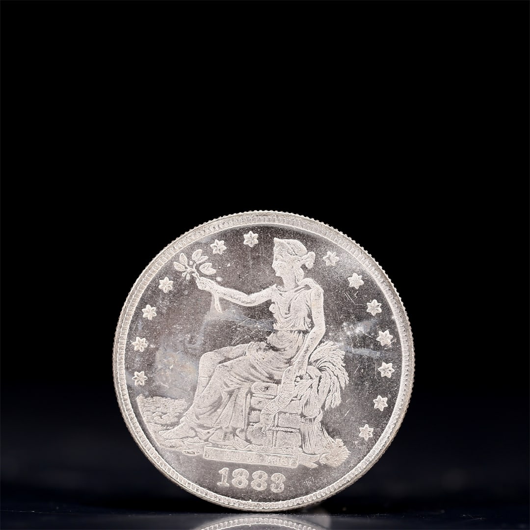 USA Trade Dollar 1883 Coin: American coin. Obverse: Liberty seated on a pedestal facing the sea to the left holding olive branches surrounded by 13 stars. IN GOD WE TRUST / LIBERTY / 1883. Reverse: An eagle holding branches with