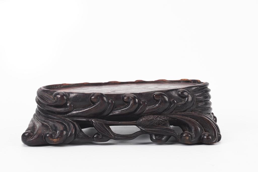 Hardwood Oval Stand, 18th-19th Century: China, 18-19th century Dimensions: 4 1/2" (11.4cm) L, 7 5/8"( 19.4cm) W, 2" (5cm) H Hardwood carved stand decorated with leafy patterns. 18-19世纪 硬木雕花底&