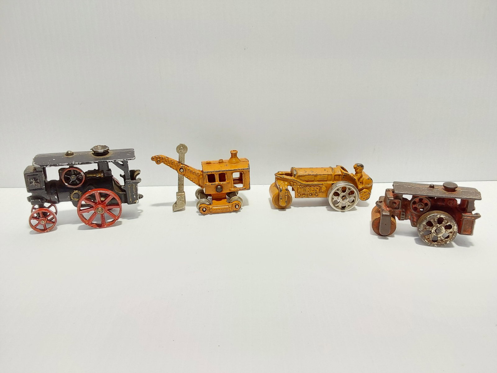 (4) cast iron toys: Steam engine - 3 1/2" long Red roller - 2 3/4" long Shovel - 3 1/2" long Orange roller - 3 1/2" long