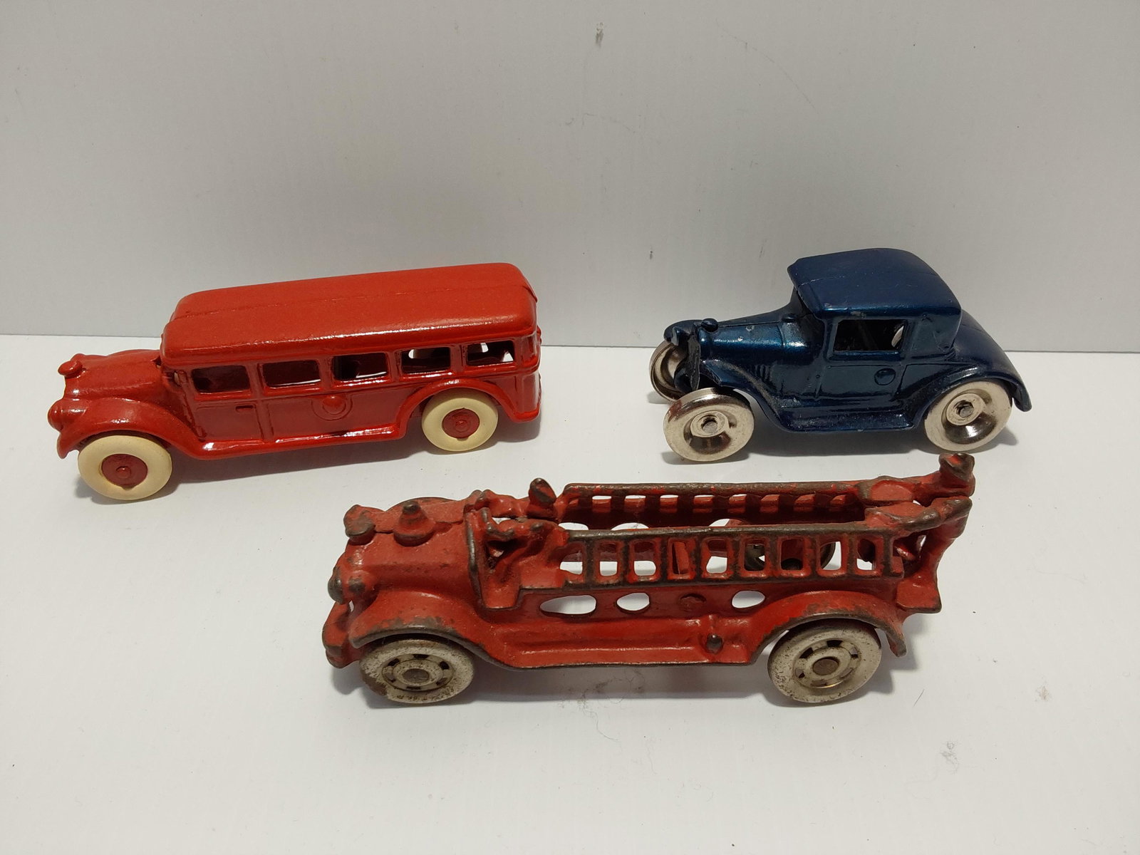 (3) cast iron toys: bus - 5" long fire truck - 5" long blue Arcade car - 4" long