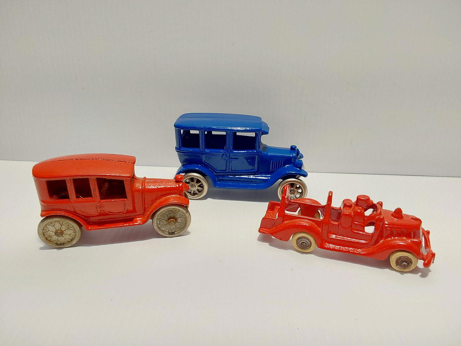 (3) cast iron toys: fire truck (missing ladders) - 5" long red car - 4 7/8" long blue car - 5" long