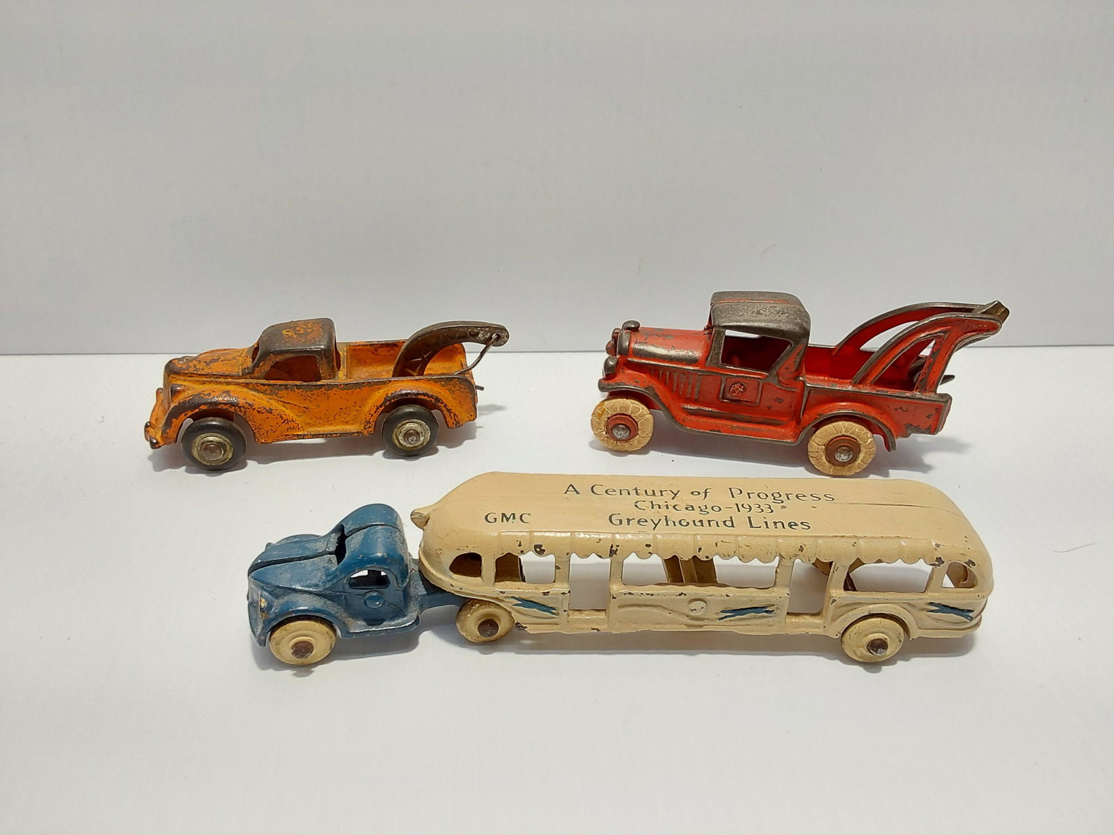 (3) cast iron toys: Greyhound bus - 7 1/4" long Red wrecker - 5" long Orange Arcade wrecker - 4 1/2" long