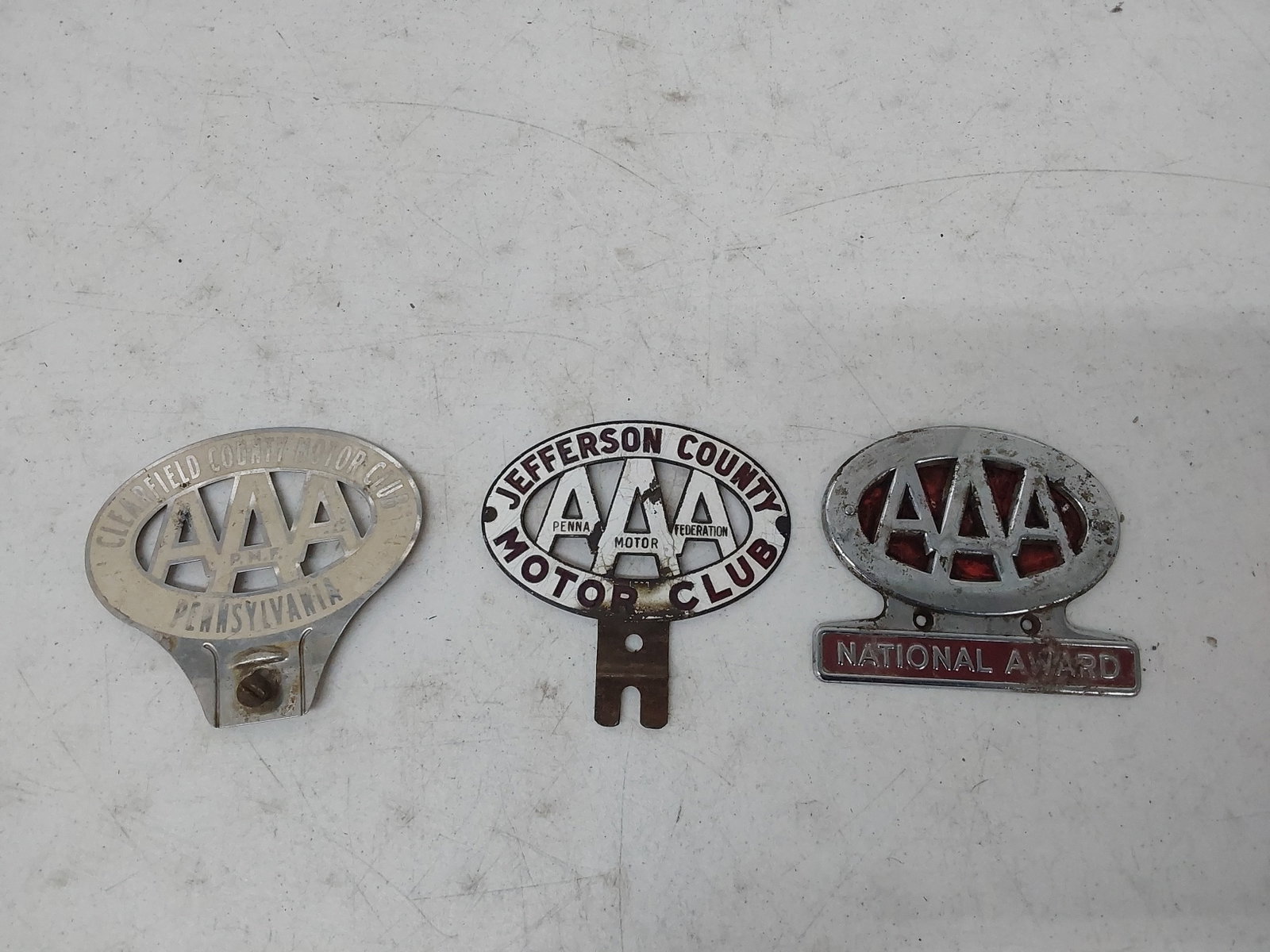 (3) Triple A license plate toppers: One is porcelain.