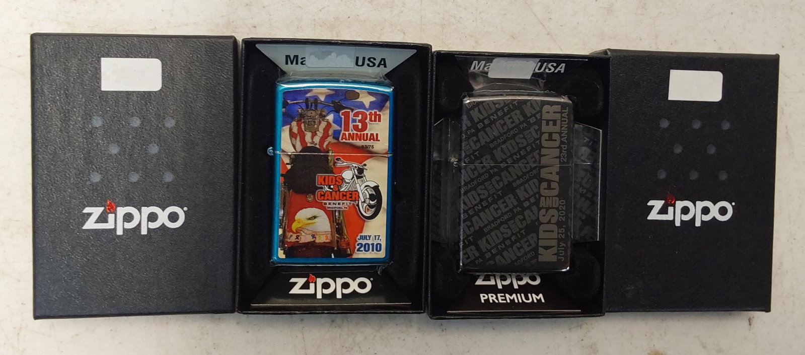 (2) unused collectible Zippo lighters: (1) 2010 13th Annual Kids & Cancer, blue high polish chrome finish Zippo lighter in box. (#63 of 75). Unused. (1) 2020 23rd Annual Kids & Cancer, high polish Black Ice 360 Deg. finish Zippo lighter in