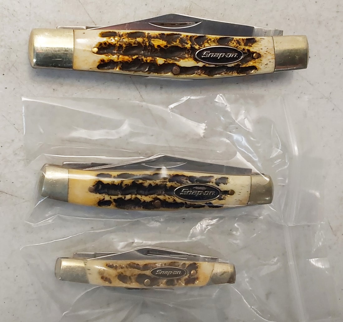 (3) Snap-on 3-blade knives: (1) 2" clip, 1 3/8" Wharncliffe and 1 1/4" Penn blades, (2 1/2" closed), imitation Stag handles with Snap-on Shield, without box. Unused. (1) 2 1/2" clip, 1 3/4" Warncliffe and 1 5/8" Penn blades, (3