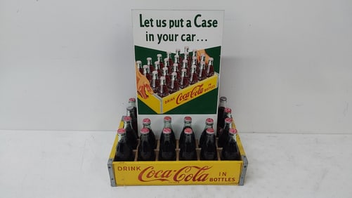 crate of Coca-Cola bottles with masonite sign