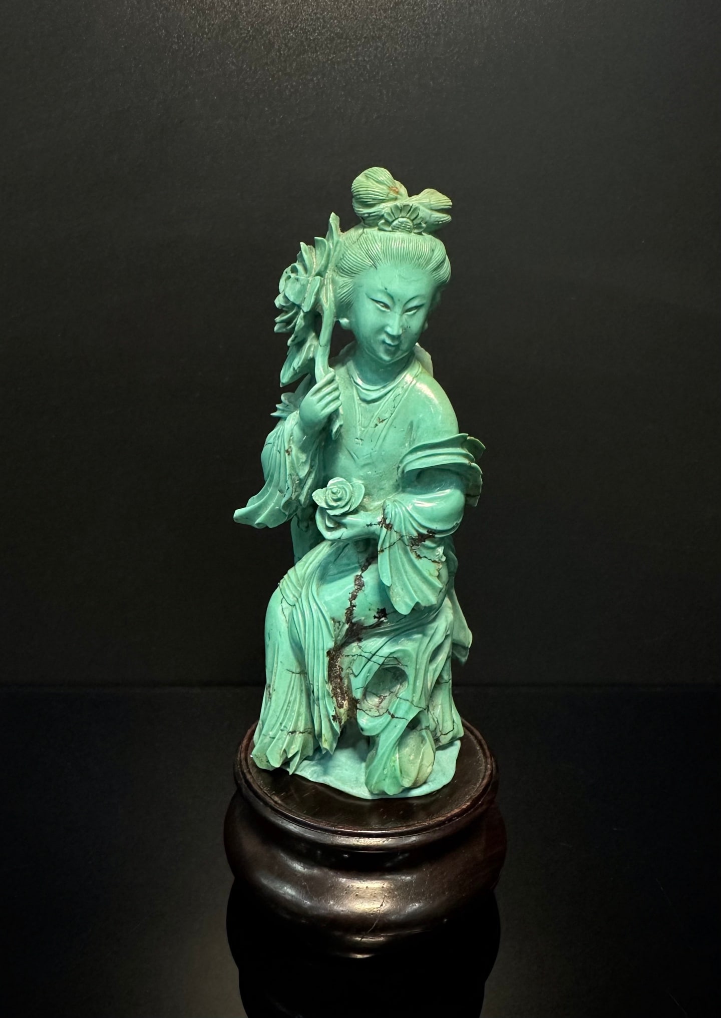 Qing Dynasty turquoise maid statue: A turquoise colored figure statue, with a dignified and beautiful appearance, delicately carved clothing folds, and holding flower branches, presenting the overall style of Eastern literati art. The s
