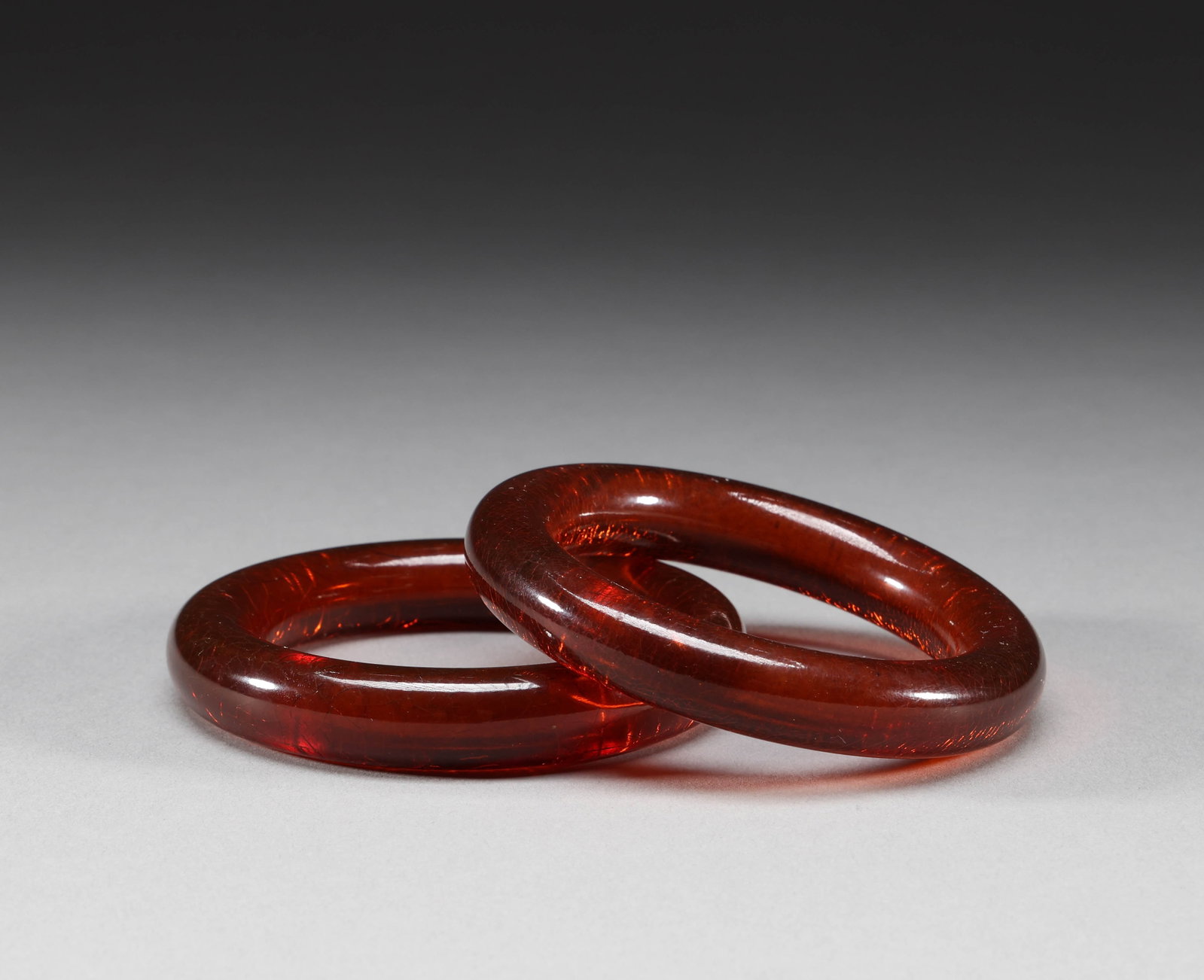 A pair of amber bracelets from the Qing Dynasty: A pair of natural amber bracelets. This pair of amber bracelets has an inner diameter of about 5.8 centimeters and weighs about 71 grams. Overall, it has a deep red transparent texture, with a warm an