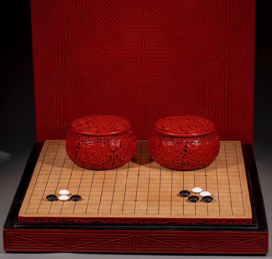 A set of carved lacquer Go: Red carved lacquer peony pattern set of Go gamesSpecification: 51 cm in length, 48 cm in width, and 8.5cm in height. The base of the carved lacquer patterned chessboard is adorned with a pair of deep 