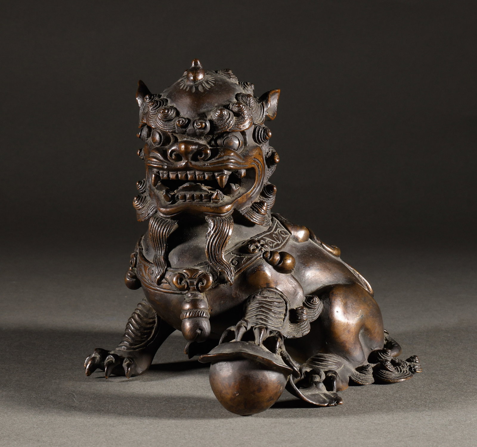 Qing Dynasty Bronze Lion Ornament: The old bronze lion ornament for playing ball is 15cm high, 17cm wide, and weighs 1327g. It is intricately carved with mane and tassels, giving the lion a majestic presence when stepping on the ball. 