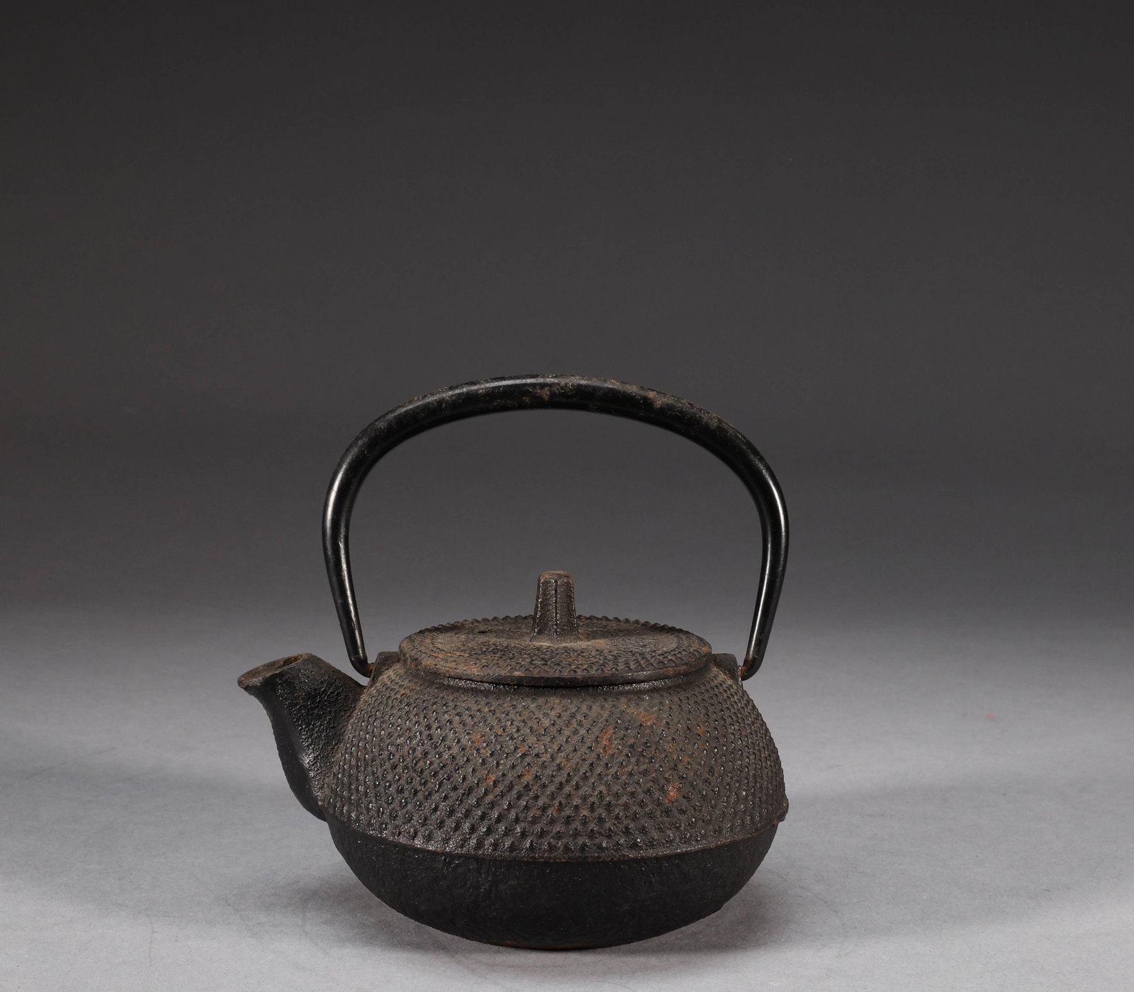 Old Japanese Iron Pot: A small cast iron teapot with herringbone pattern, 13cm high, 12cm wide, weighing 670g. It has herringbone pattern throughout the body, bridge button, original iron lifting beam, and a black leather s