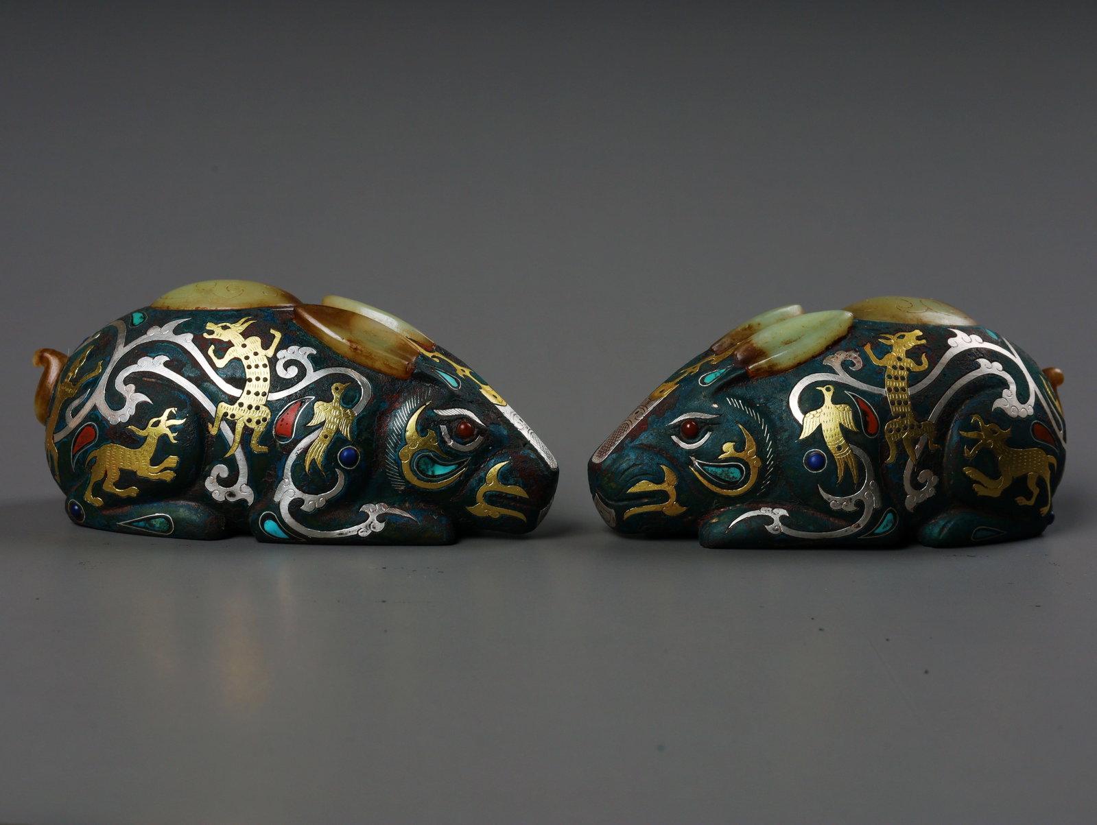 Before the Ming Dynasty, there was a pair of copper, gold, and silver inlaid with jade rabbits: Pre-Ming Pair of Bronze Rabbits Inlaid with Gold and Silver. Embodying a century of master craftsmanship, the piece stands 6.5 cm tall. Fine-grained and thickly patinated, complete in form and spirit,