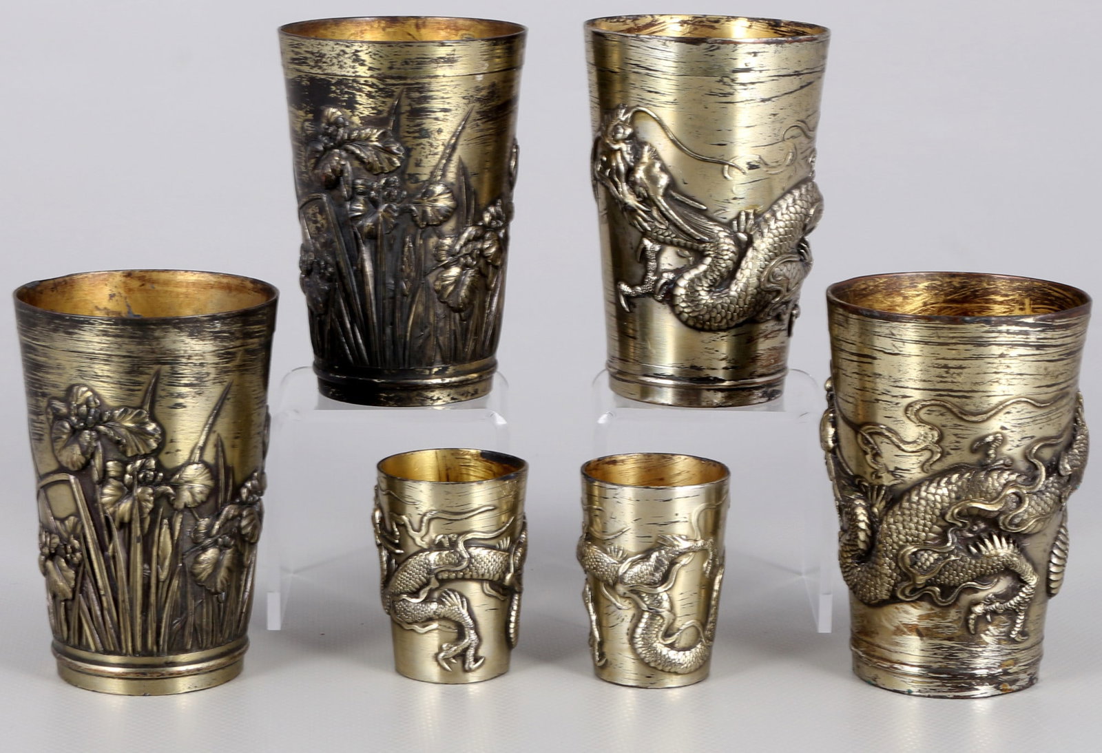 Japan 6 cups Meiji period 19th century,: Japan, Meiji period 1868-1912, 6 metal cups, four of which are engraved with flying dragons and two with lotus flowers, 4 x H 8.8 cm x D 5.8 cm, 2 x H 4.8 cm x D 3.3 cm, a Stand ring bent