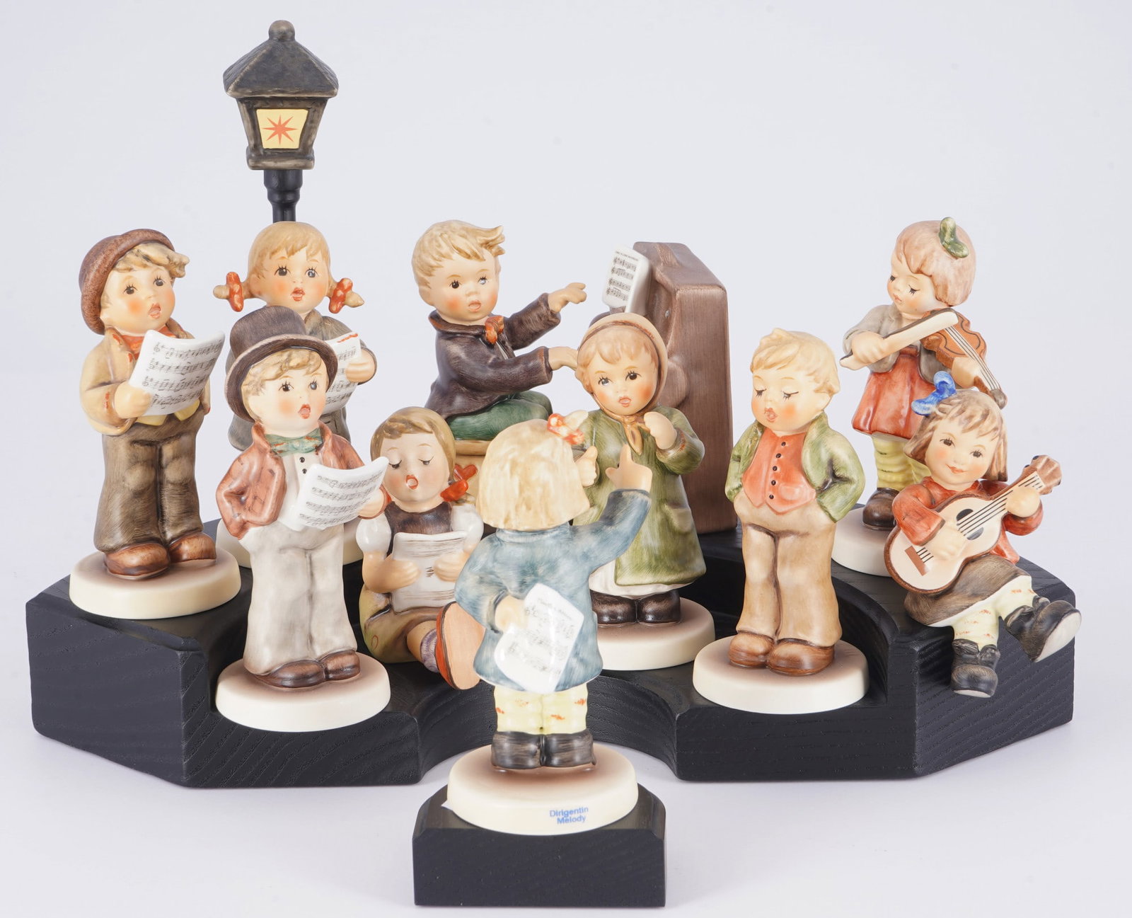 Hummel / Goebel 10 musician children on platform,: porcelain, blue company mark, design after Maria Innocentia HUMMEL (1909-1946), with signature, various children's figures including a piano player and a conductor on a pedestal, 10 x H 6.5 - 10.5 cm,
