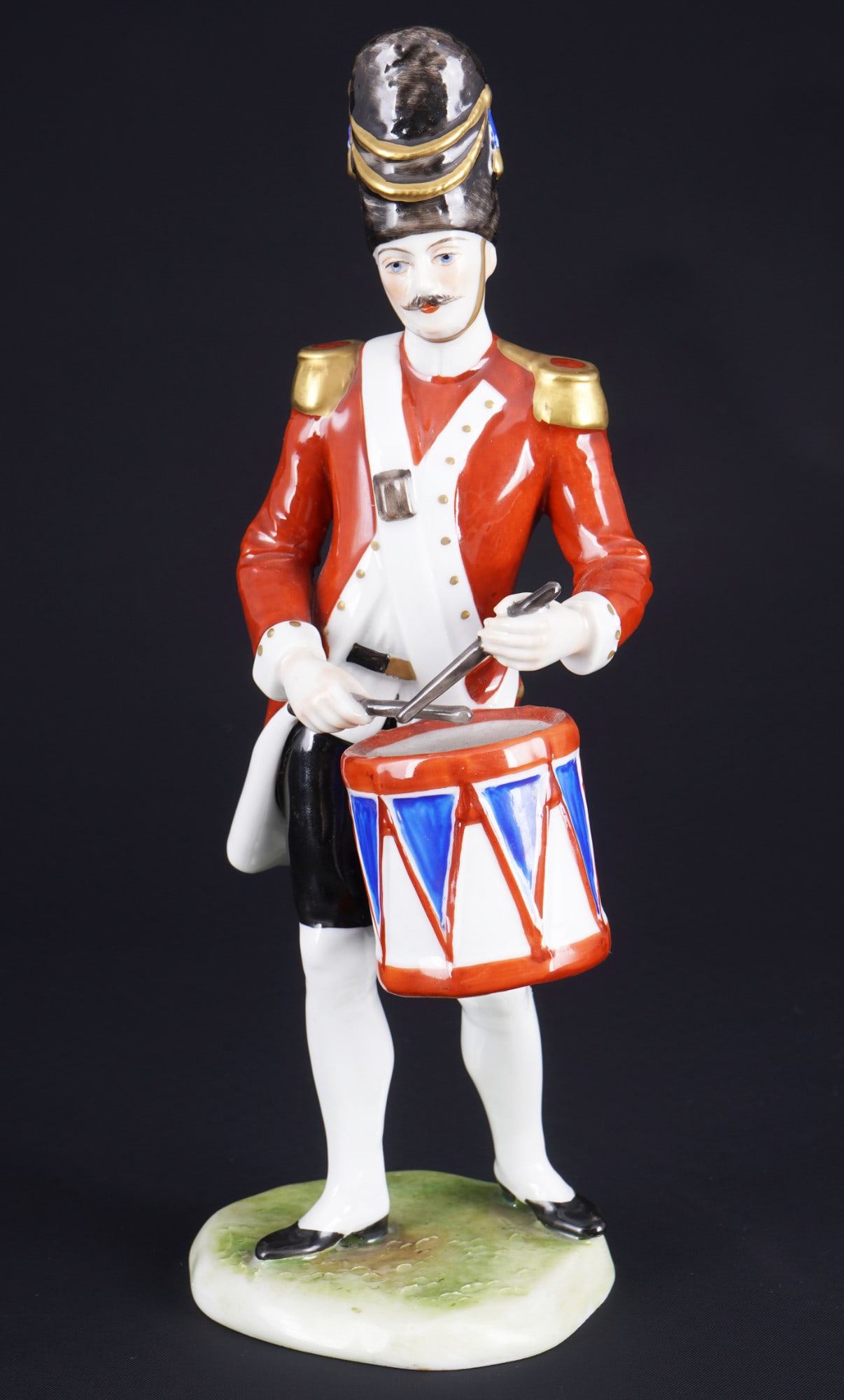Oldest Volkstedt british redcoat drummer,: porcelain, blue company mark, gold lettering "Cavalier - trompetie" on the base, model no. V20596, english drummer in red and white uniform with epaulettes, a distinctive tall grenadier cap and a blue