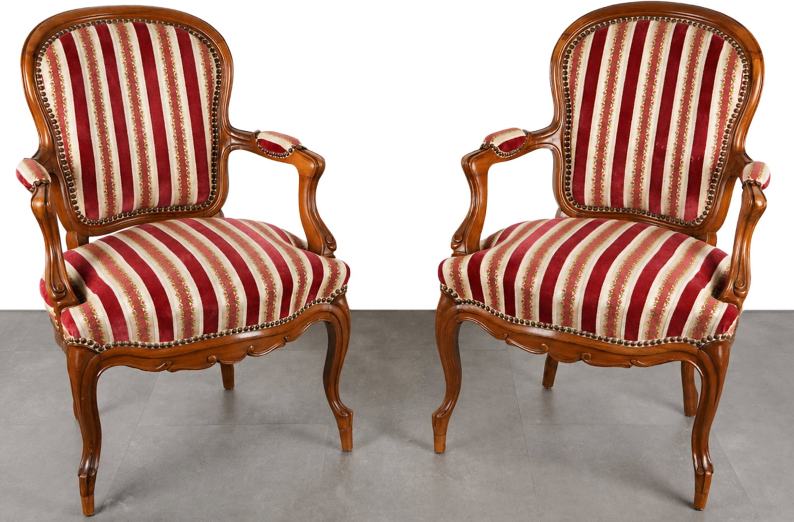 Pair of French armchairs in the Louis-Philippe style,: Elegant pair of upholstered armchairs in the Louis-Philippe style, crafted from solid walnut, with curved armrests and cabriolet-style legs. The backrests and seats are fully upholstered in a red and