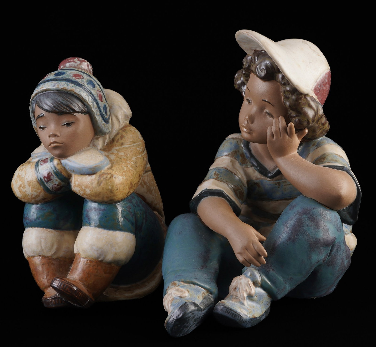 Lladro / Nadal eskimo boy and boy with cap,: porcelain, Spain, blue company mark, seated boy with cap from the Long Day porcelain series H 19 cm x W 19.5 cm and Eskimo boy design by Francisco Catal? H 17 cm x W 9.5 cm