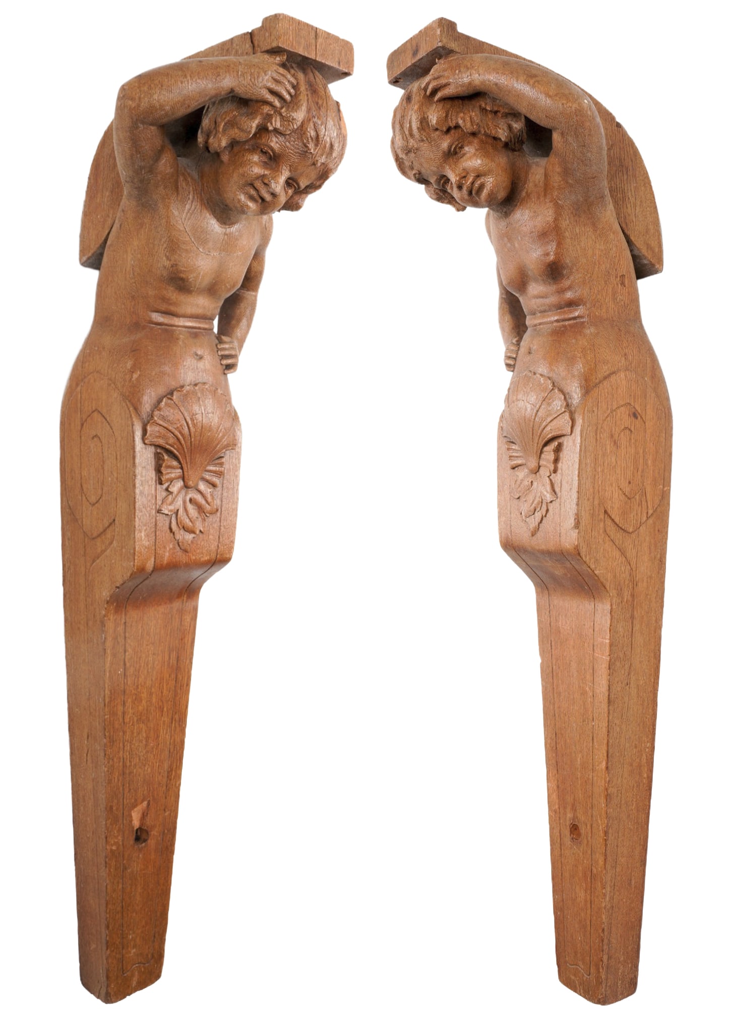 A pair of large figureheads,: Oak wood, crafted as mirror-image counterparts, each depicting a sculpted youth with his arm raised above his head, an elongated, tapering body with relief shell and leaf decoration, each approx. H 10