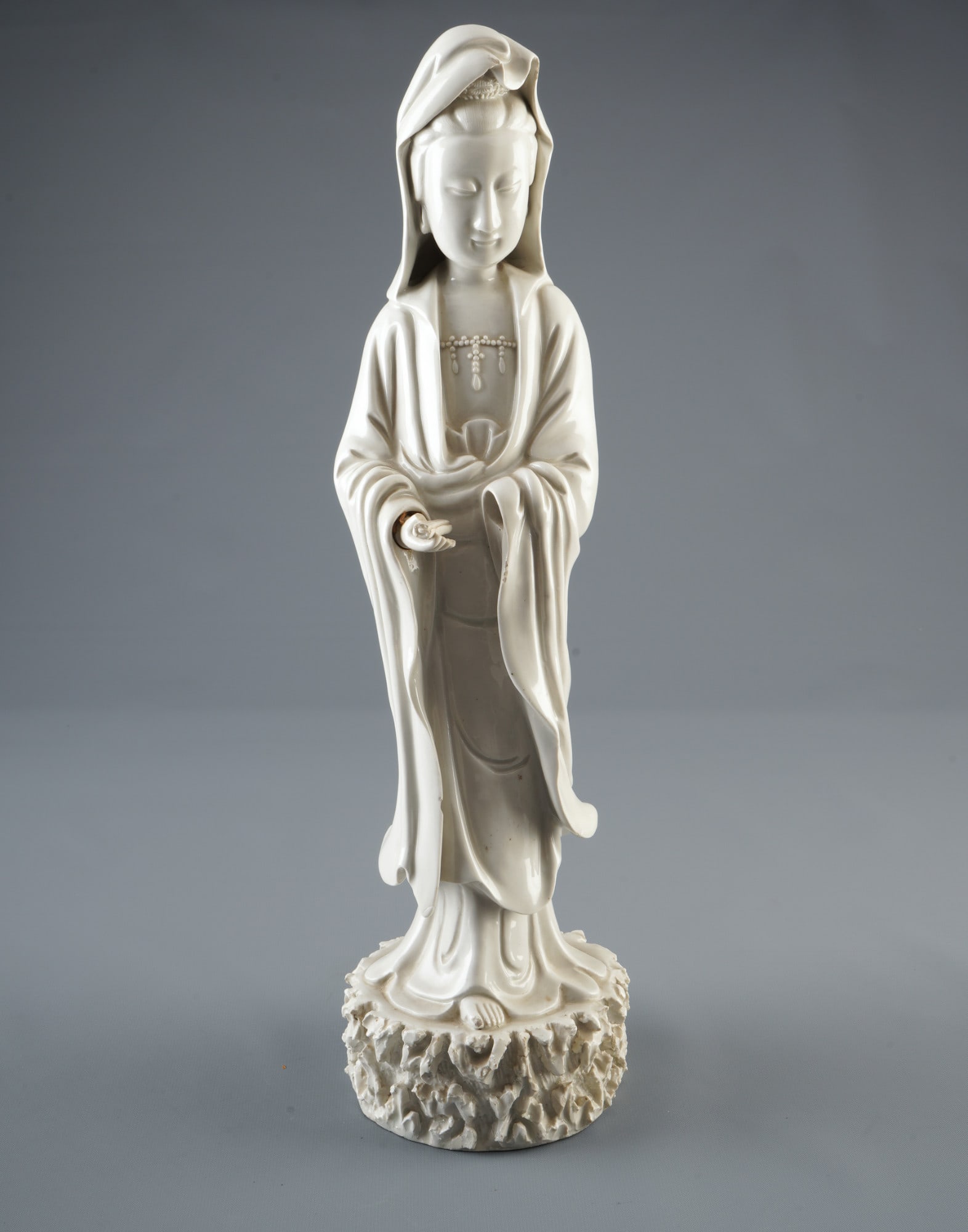 Large standing Dehua-Guanyin figure with scroll, China, Qing Dynasty,: Porcelain, China, Qing Dynasty (1644-1911), large standing Dehua-Guanyin figure with a scroll in its right hand, standing on a rock, H 45 cm x D 12 cm, damage to the right hand, left hand missing, Ger