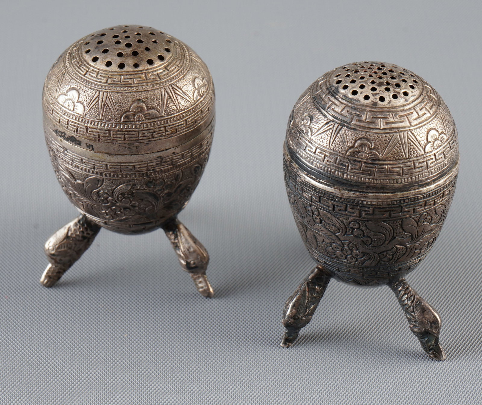 Pair of silver salt and pepper shakers, China, Qing Dynasty: Silver, China, Qing Dynasty (1644–1911), pair of egg-shaped silver salt and pepper shakers, each resting on three animal head feet, base stamped with the seal “Shenglong”, H 4.8 cm, weight 2