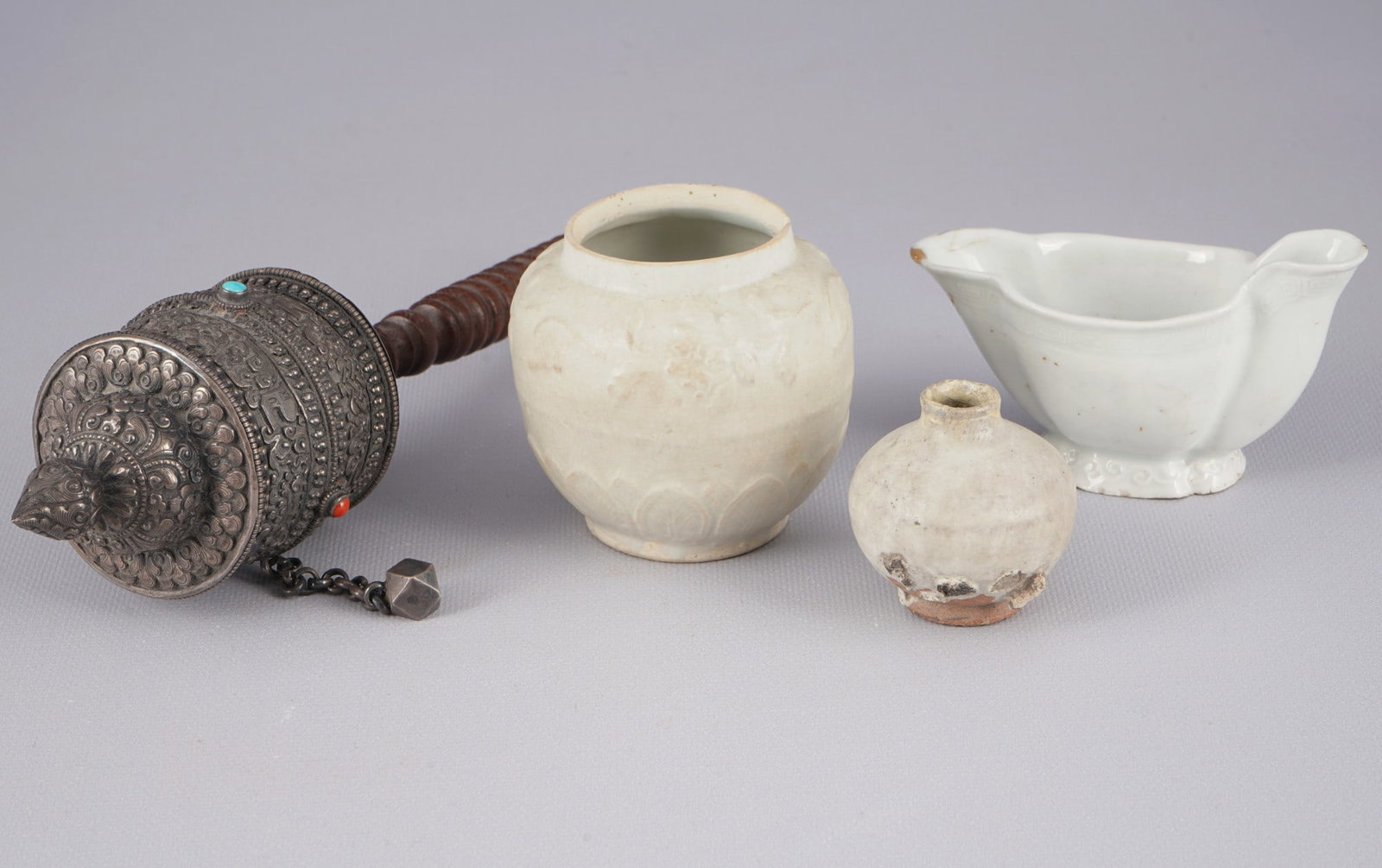 Bronze prayer wheel and three porcelain objects, China/Tibet,: Bronze, porcelain, China/Tibet, bronze prayer wheel and three porcelain objects, prayer wheel L 28 cm, porcelain H 8 cm x D 8 cm and others, with a small chip