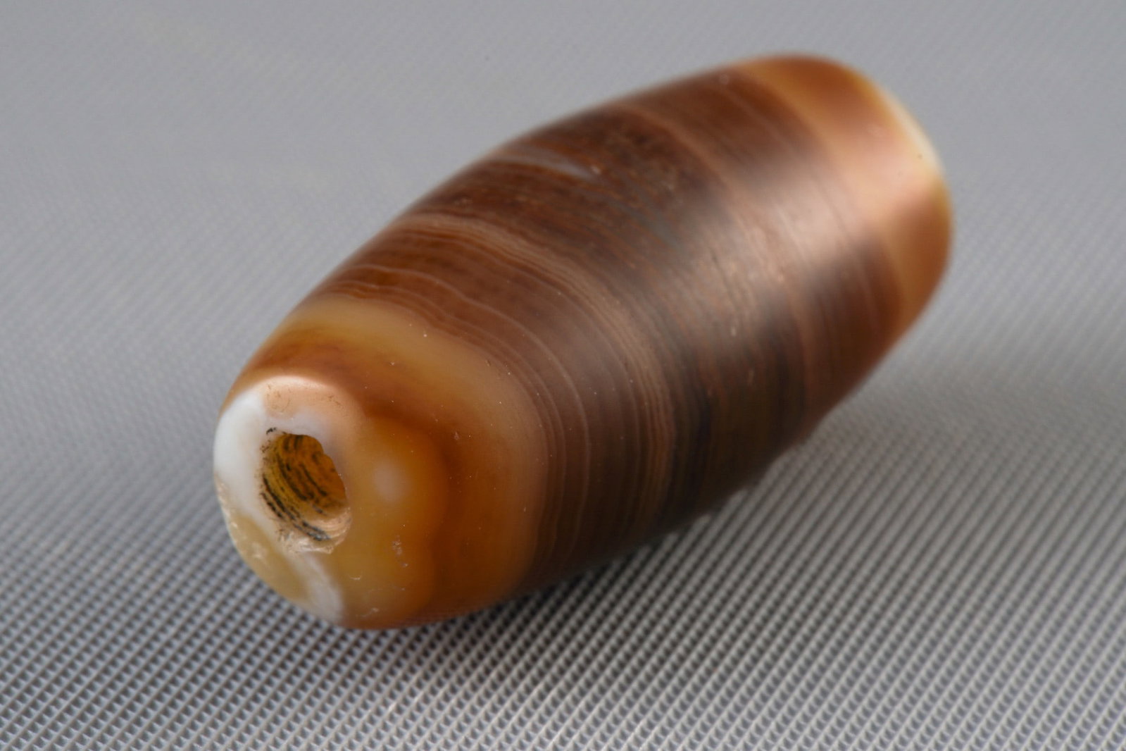 Buddha Eye Dzi Bead, China/Tibet,: Amulet, China/Tibet, Buddha Eye Dzi bead made of natural banded agate (striped agate), the cross-section shows distinct concentric or wavy layers in the colors honey brown, dark brown, grey-black and 