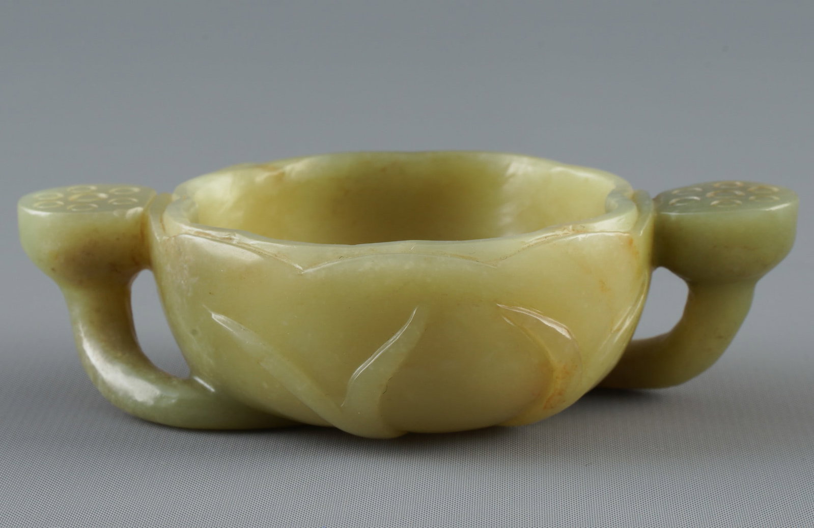 Hetian jade lotus leaf-shaped washbasin with double handles, China, Republican period: Jade, China, Republican period, lotus leaf-shaped washbasin with double handles, made of light green Hetian nephrite, in the shape of a natural lotus leaf with a wavy edge and two lotus-shaped handles