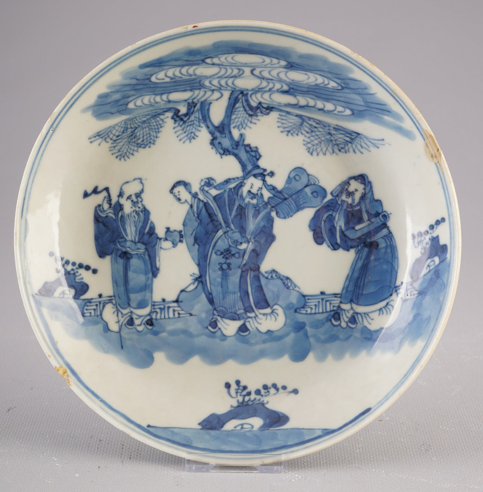 Blue and white plates, China, Qing Dynasty: Porcelain, China, Qing Dynasty (1644–1911), blue and white plates with figural scenes of scholars under a stylized pine tree, with a 4-character Kangxi mark on the base, diameter 18.8 cm, small chip