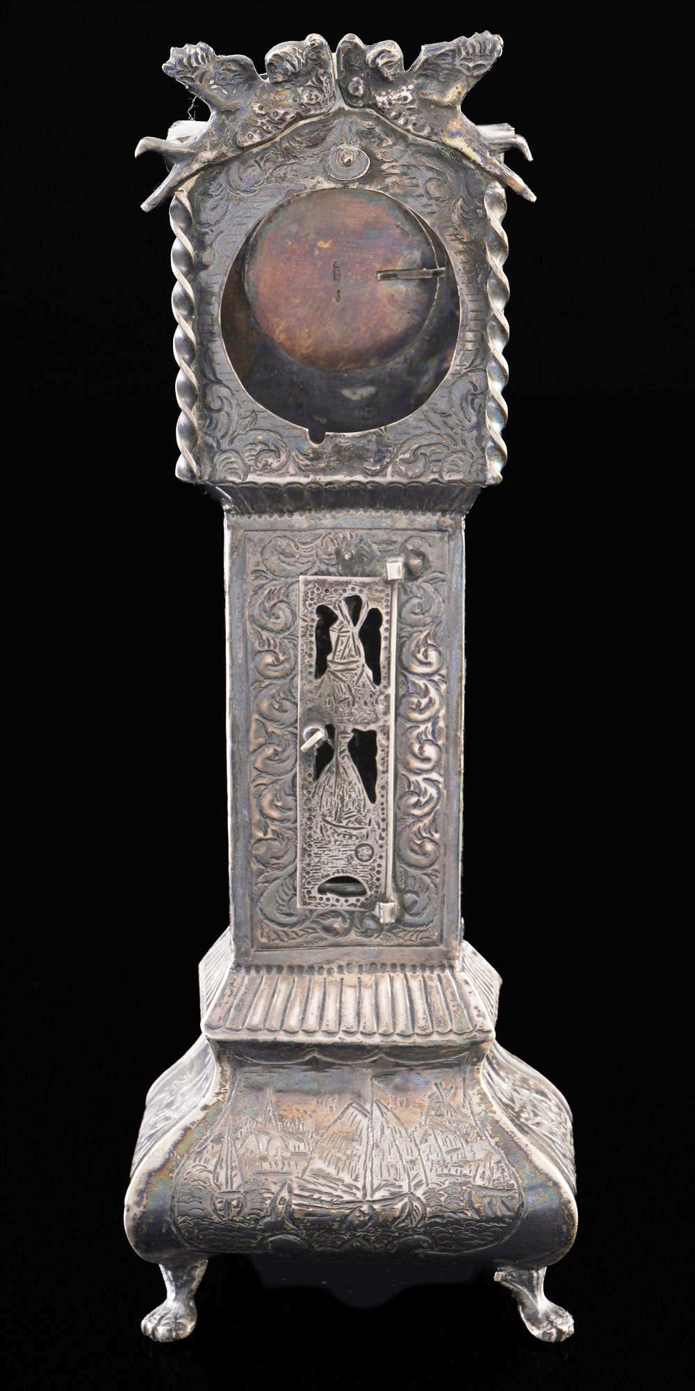 833 silver pocket watch stand in the form of a grandfather clock, Netherlands, 19th century.: Silver 833/1000, stamped J.P.H + lion 2, body decorated all over with reliefs, including typical Dutch motifs with sailing ships, windmills and floral tendrils, H 20.5 cm x W 7 cm x 4 cm, outer diamet