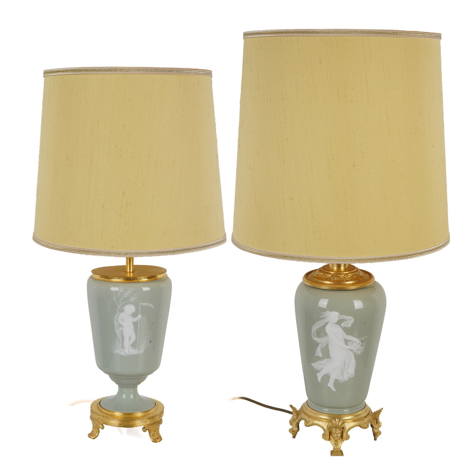 Two table lamps with pate-sur-pate and bronze mounts,: France, celadon green porcelain bodies with white figurative and floral relief decoration, gilded bronze/metal mounts with decorative feet, 1x H 69 cm x D 14 cm, shade D 36 cm, and 1x H 57 cm x D 12 c