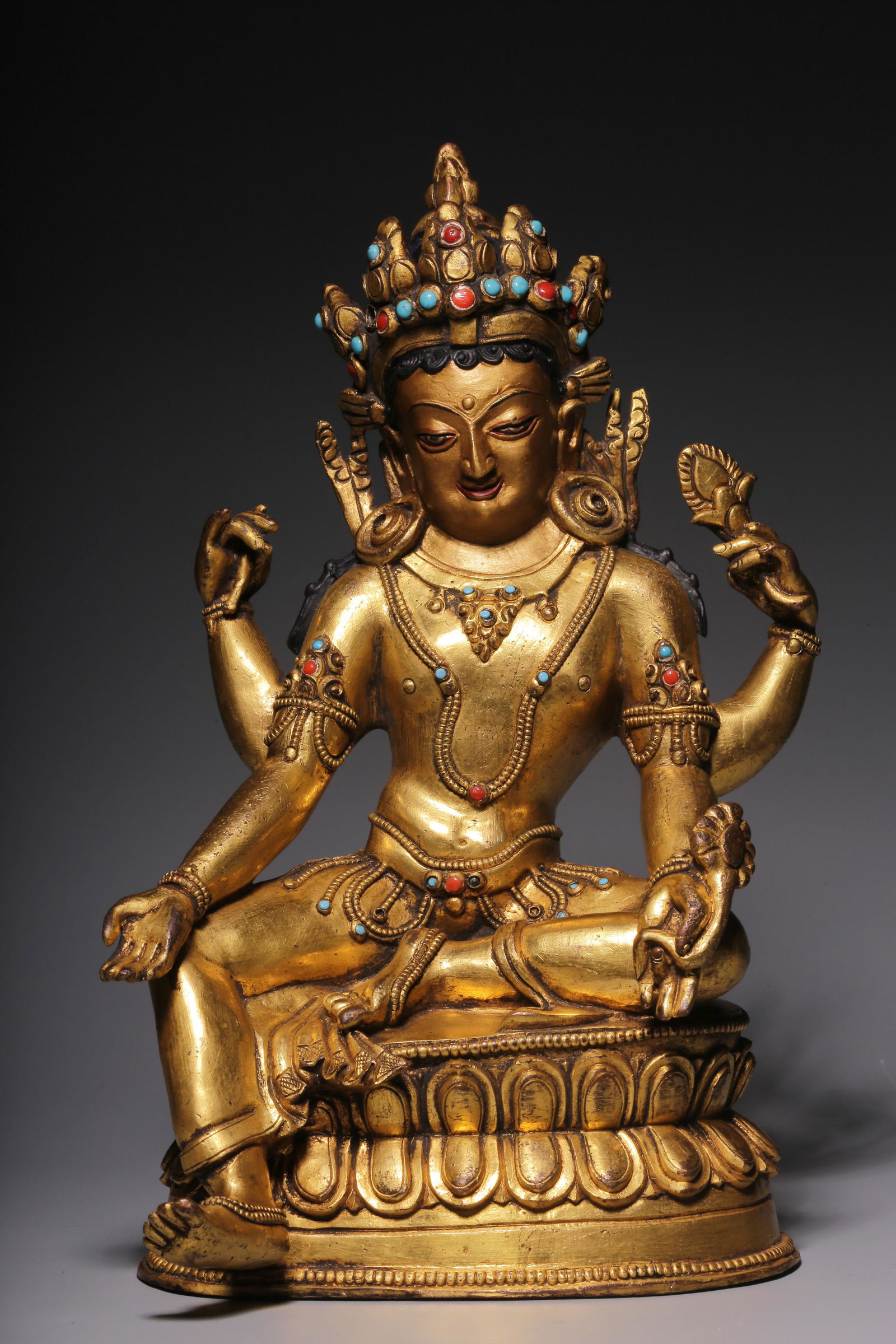 In the Qing Dynasty, a sitting statue of Guanyin with four arms inlaid with treasure and gilt copper (1 of 7)