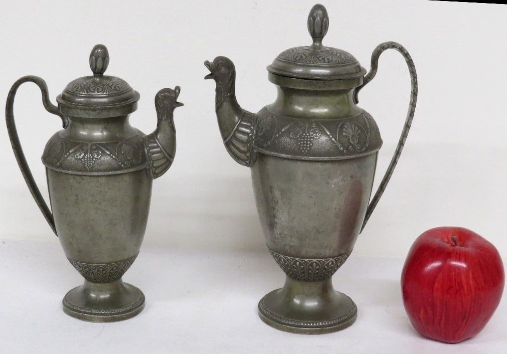Pr. Of 1855 Ostrich Head Pewter Wine Carafe / Pitchers: A pair of mid-19th Century elaborately decorated lidded pewter carafe's or pitchers featuring ostrich head spouts, each monogrammed H.L. with date of 1855 under spouts. Smaller of the pair has minor d