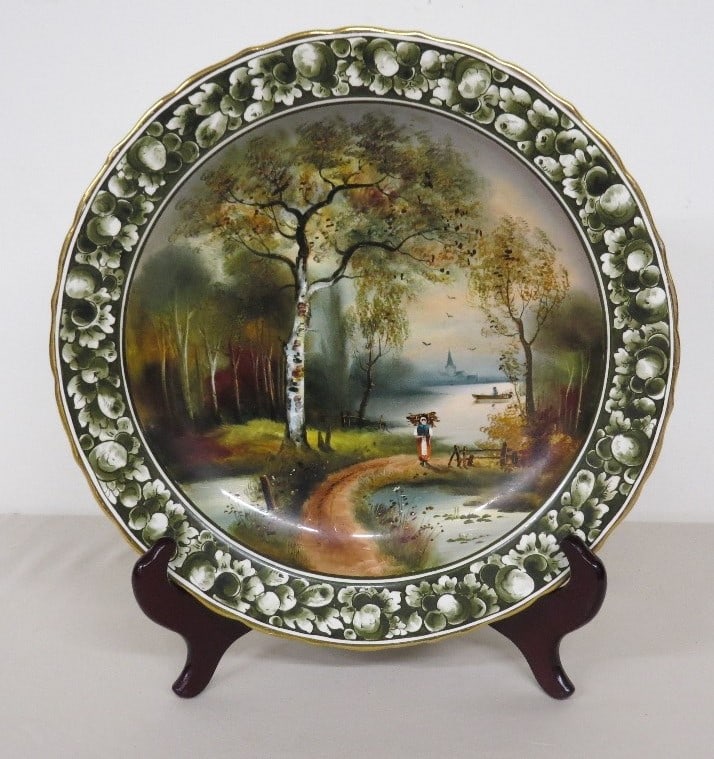 Early 20th C. German Porcelain Charger of Woodland Scene: A very attractive European handpainted charger or hanging plate depicting a young woman walking through the woods with a bundle of sticks on her back, titled Handmalerie which is German for handmaiden