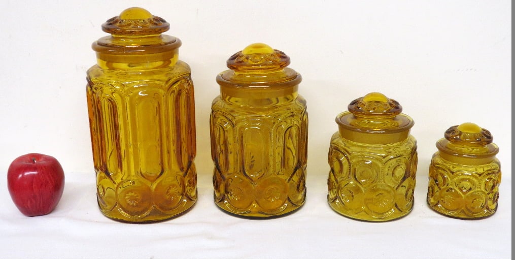 L.E. Smith Glass Co. Honey Amber Moon & Stars Canister Jar Set: A set of 4 L.E. Smith Glass Co. Moon & Stars Canister Jars ranging from 5" to 11.5" in height. Ground lids/inner rims for tight fit. Chipping to inner rim of the tallest with one chip, and a bit more 
