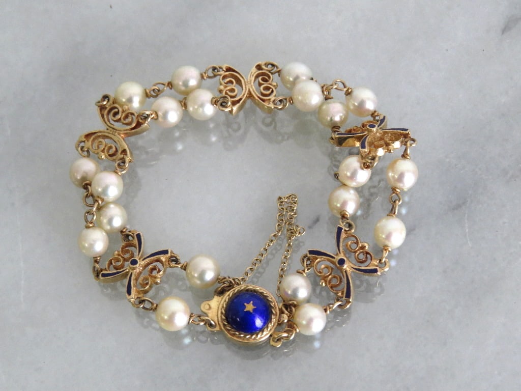 14kt Butterflies and Pearls With Inlays & Blue Enameling: Estate jewelry, this lovely 14kt marked bracelet with safety chain features butterfly links inlaid with blue enameling and real pearls A blue enameled centerpiece with gold star. Bracelet weights 15.7