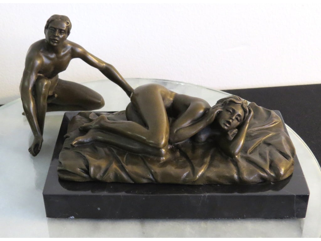 An Erotic Bronze 2pc Sculpture Fellatio by Mario Nick: A lost wax method erotic bronze sculpture on black marble with nude woman reclining on her side, with her partner ready to be pleasured, his hand reaching for her nether regions. Signed Nick, for Mari