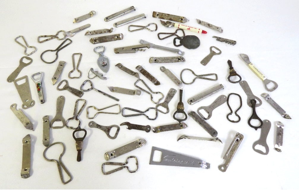 Lot of Vintage Bottle Openers: A table lot of vintage "church" keys and bottle openers, 64 in total, brewery advertising primarily. Note - This lot can be shipped in-house, you do not have to use the LiveShipping program.